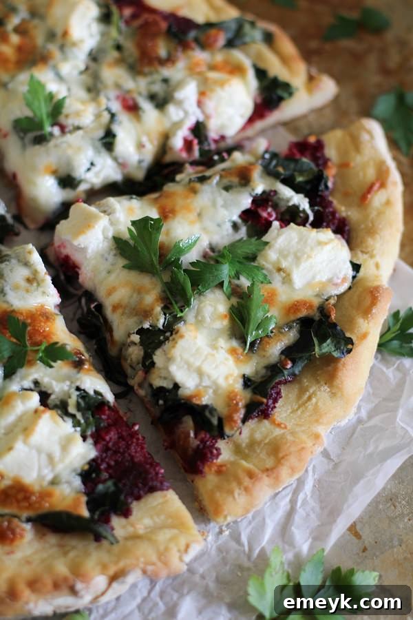 Artistic Beet Pesto Pizza generously topped with kale and creamy goat cheese.