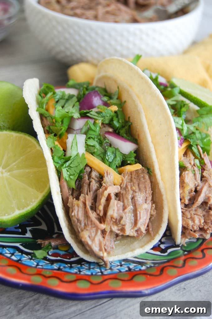Slow Cooker Shredded Beef Tacos with fresh garnishes like cilantro and lime