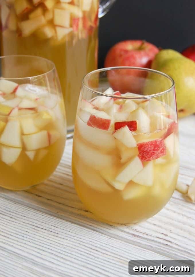 Close-up of a pitcher filled with Sparkling Apple Pear Sangria, showing fresh fruit slices.