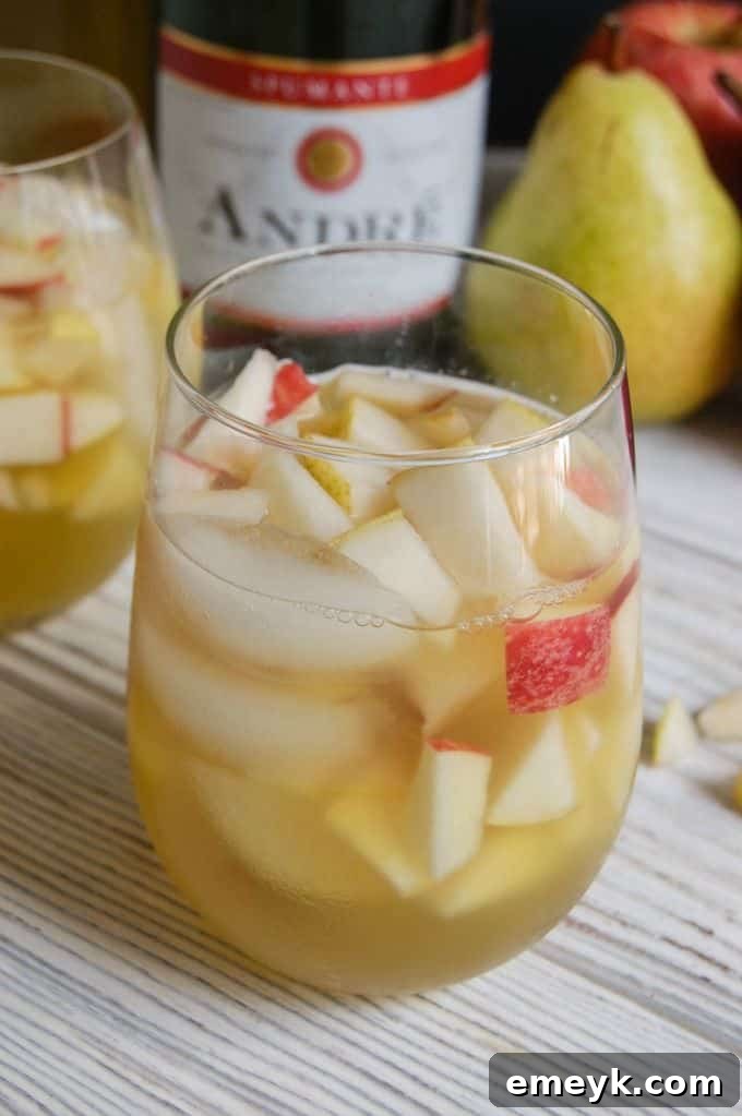 Two glasses of Sparkling Apple Pear Sangria clinking together in a celebratory toast.