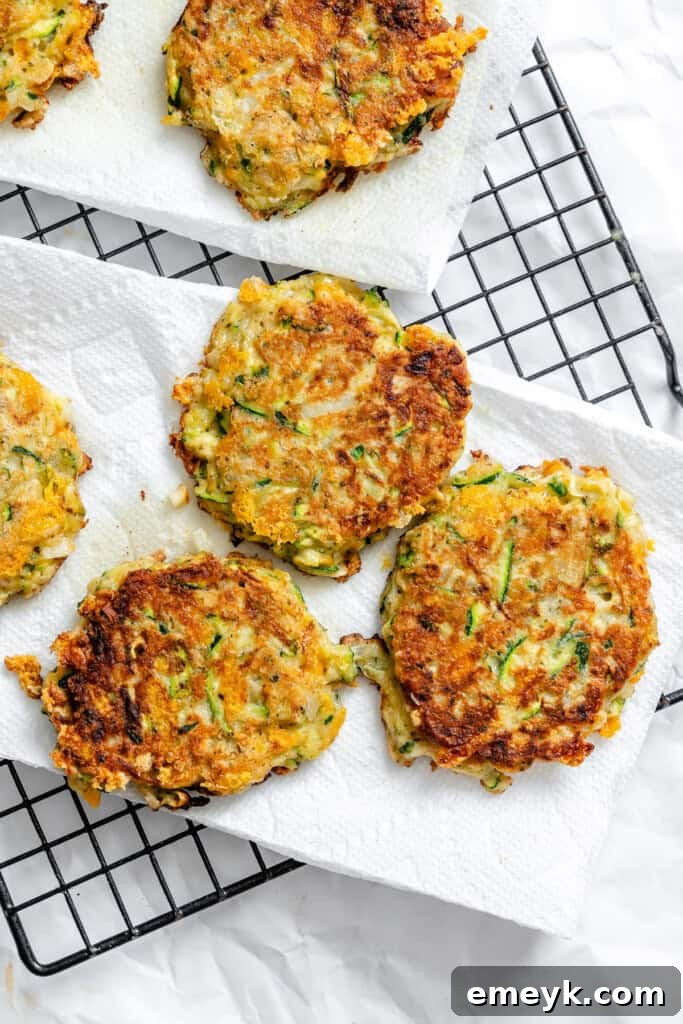 Cooked zucchini fritters resting on a baking rack to drain excess oil and maintain crispness.
