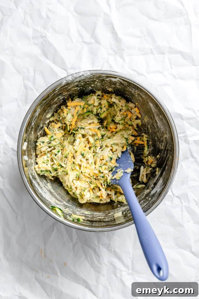 Zucchini fritter batter mixed in a bowl, showing all ingredients combined before cooking.