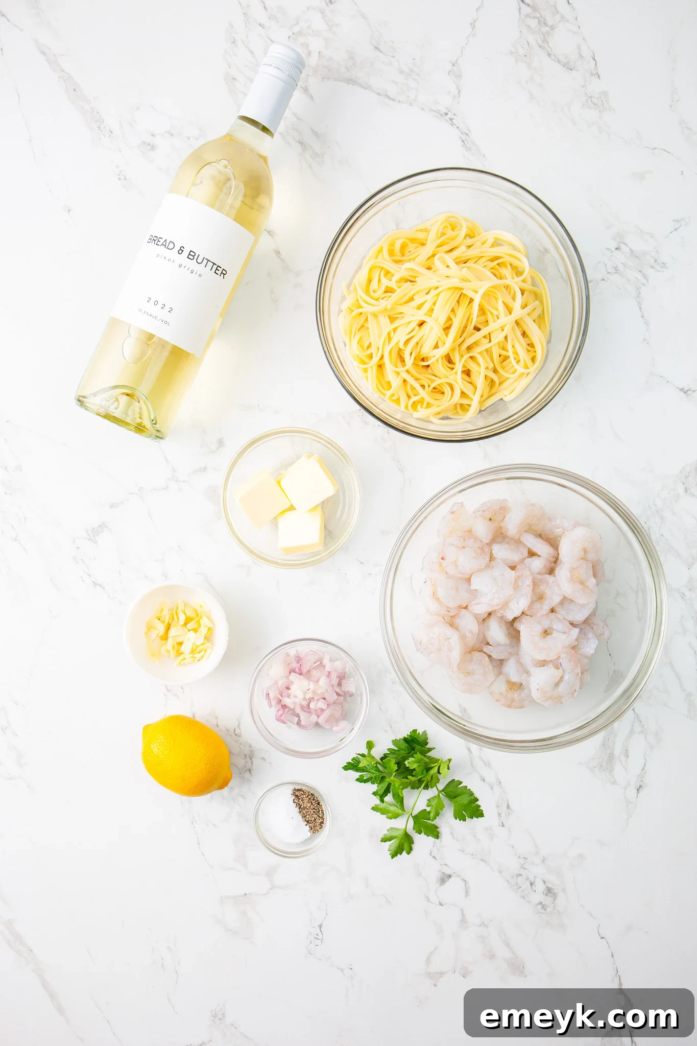 A flat lay of fresh ingredients for Lemon Garlic Shrimp Pasta including shrimp, lemon, garlic, parsley, and sun-dried tomatoes.