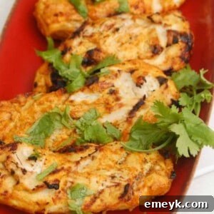 Tandoori Grilled Chicken on a red platter, garnished with fresh herbs.