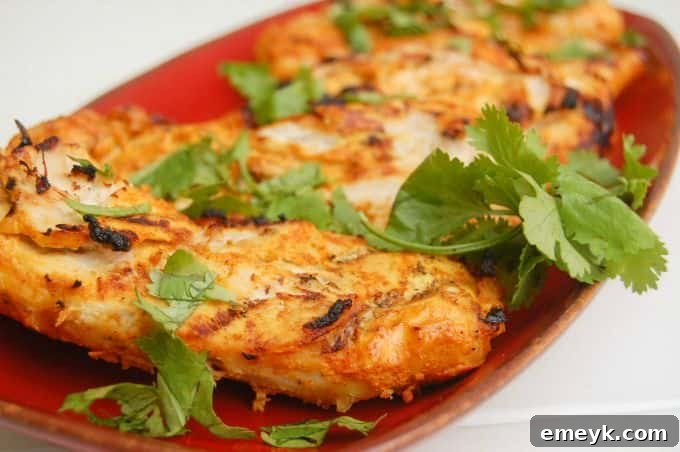 Close-up of Tandoori Grilled Chicken pieces on a grill, showcasing perfect char marks and golden color.