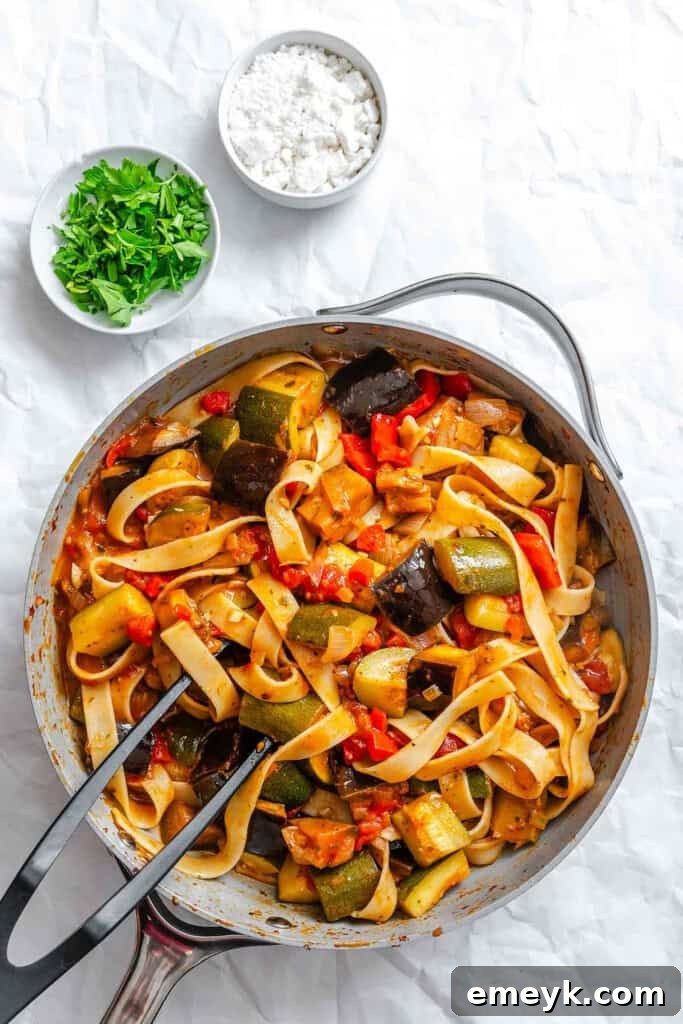 Pappardelle pasta being tossed with the homemade ratatouille sauce in a skillet.