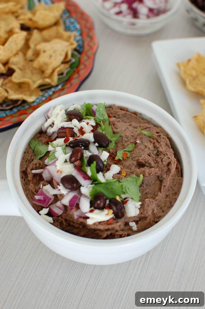 Serving bowl of Black Bean Dip with chips and garnishes