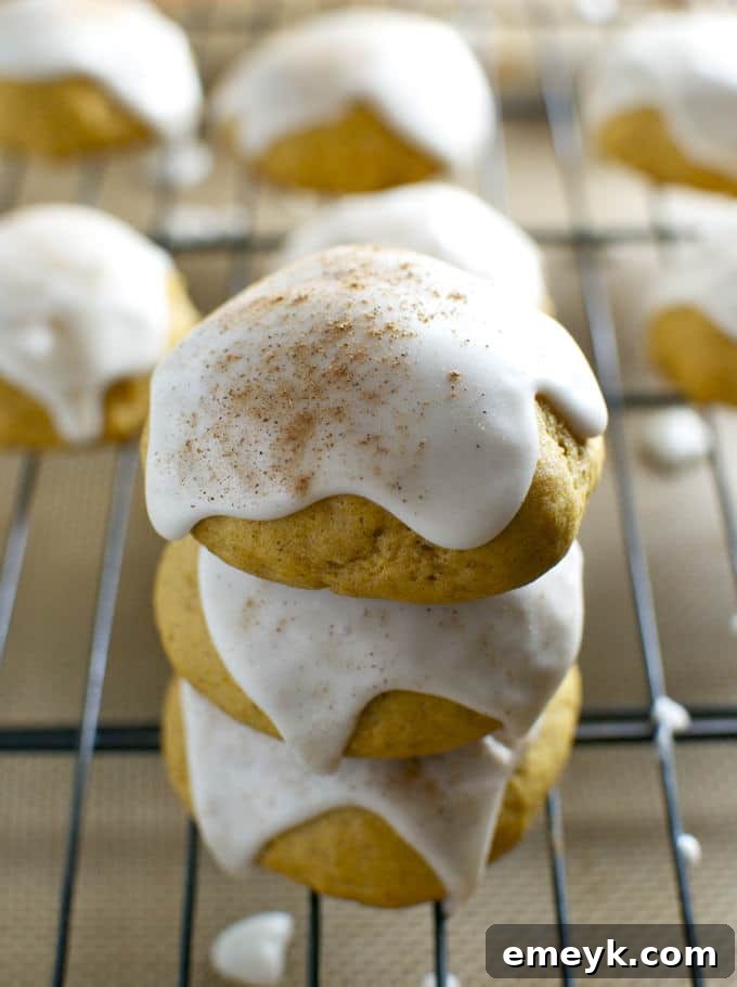 Irresistible Thanksgiving Treats 4 Soft, round pumpkin cookies topped with a smooth, glossy maple glaze, presented on a white plate.