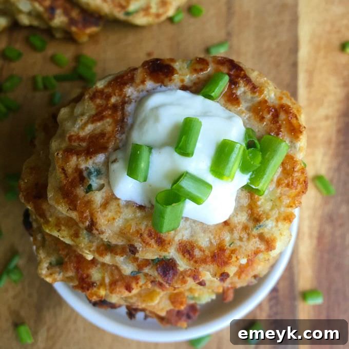 Golden brown Cheesy Zucchini Fritters stacked on a plate