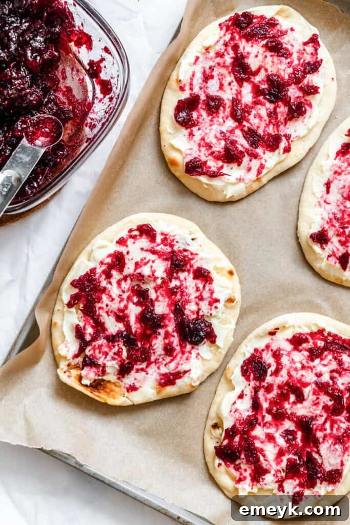 Orange cranberry sauce being spooned onto brie-covered naan