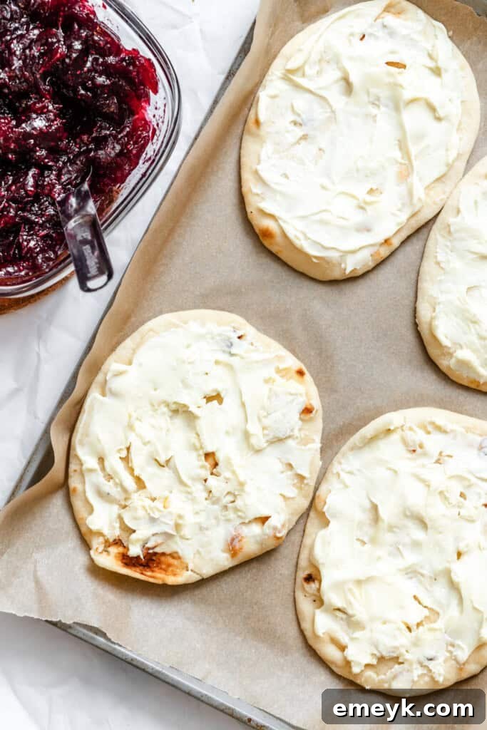 Brie cheese being spread onto a mini naan bread