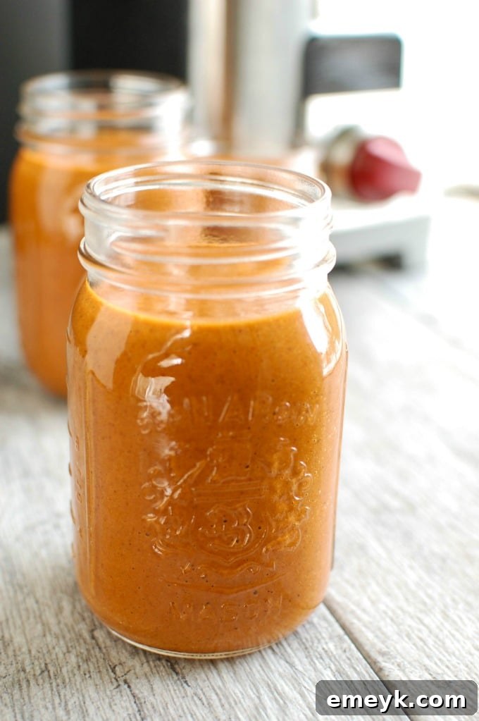 Blender with ingredients ready to make homemade enchilada sauce, with a mason jar in the background for storage.