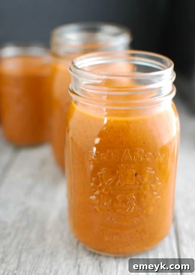 A mason jar of freshly made homemade enchilada sauce, ready for use or storage, against a rustic background.