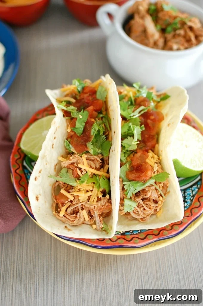 Fall-Apart Slow Cooker Pork Tacos 2 Slow Cooker Shredded Pork Tacos - A mouth-watering close-up of tender shredded pork tacos garnished with fresh cilantro and lime.