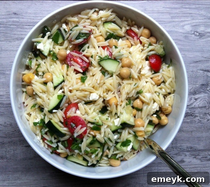 A colorful Summer Orzo Pasta Salad, featuring fresh vegetables and feta cheese, in a large bowl