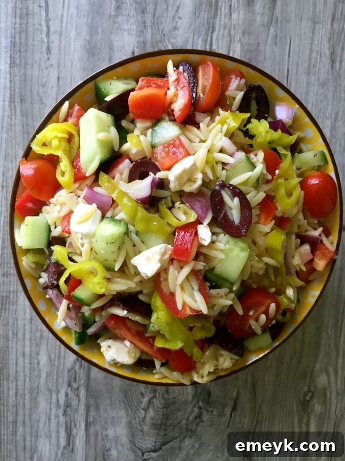 A bowl of Greek Orzo Pasta Salad, garnished with fresh herbs and feta cheese