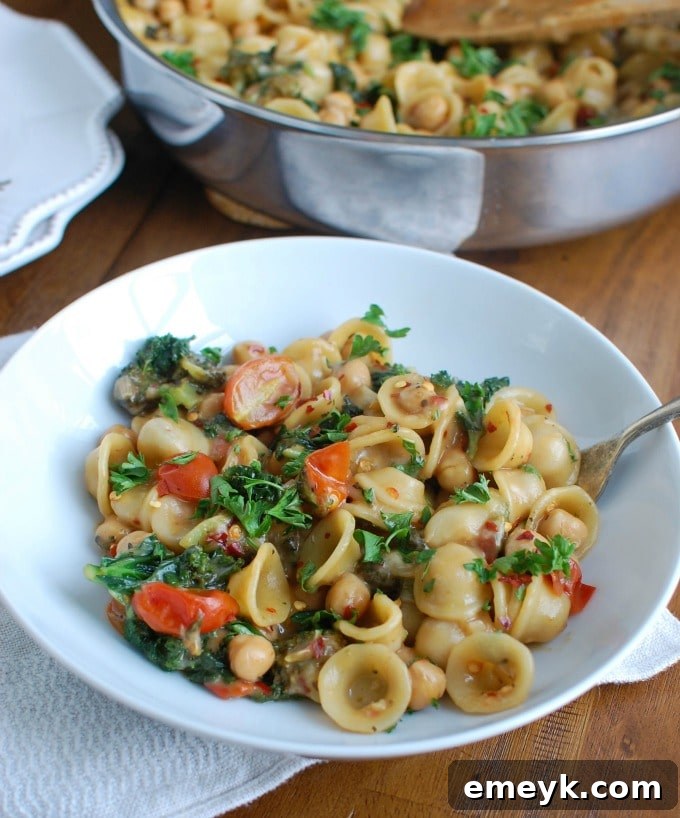 One Pot Chickpea Kale Pasta Recipe in a pan with a serving spoon.