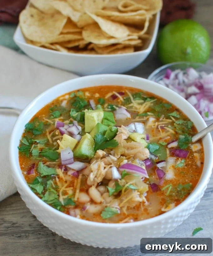 A steaming bowl of Slow Cooker White Chicken Chili, garnished with fresh cilantro and vibrant red onion, ready to be enjoyed.