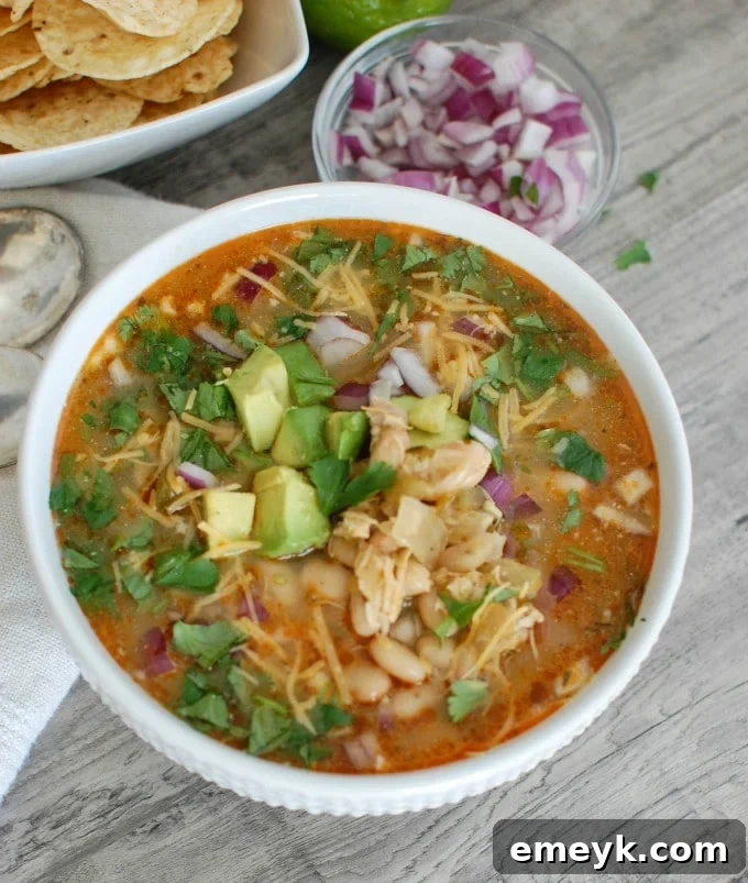 A bowl of Slow Cooker White Chicken Chili on a wooden surface, with a spoon and napkin, hinting at a cozy meal.