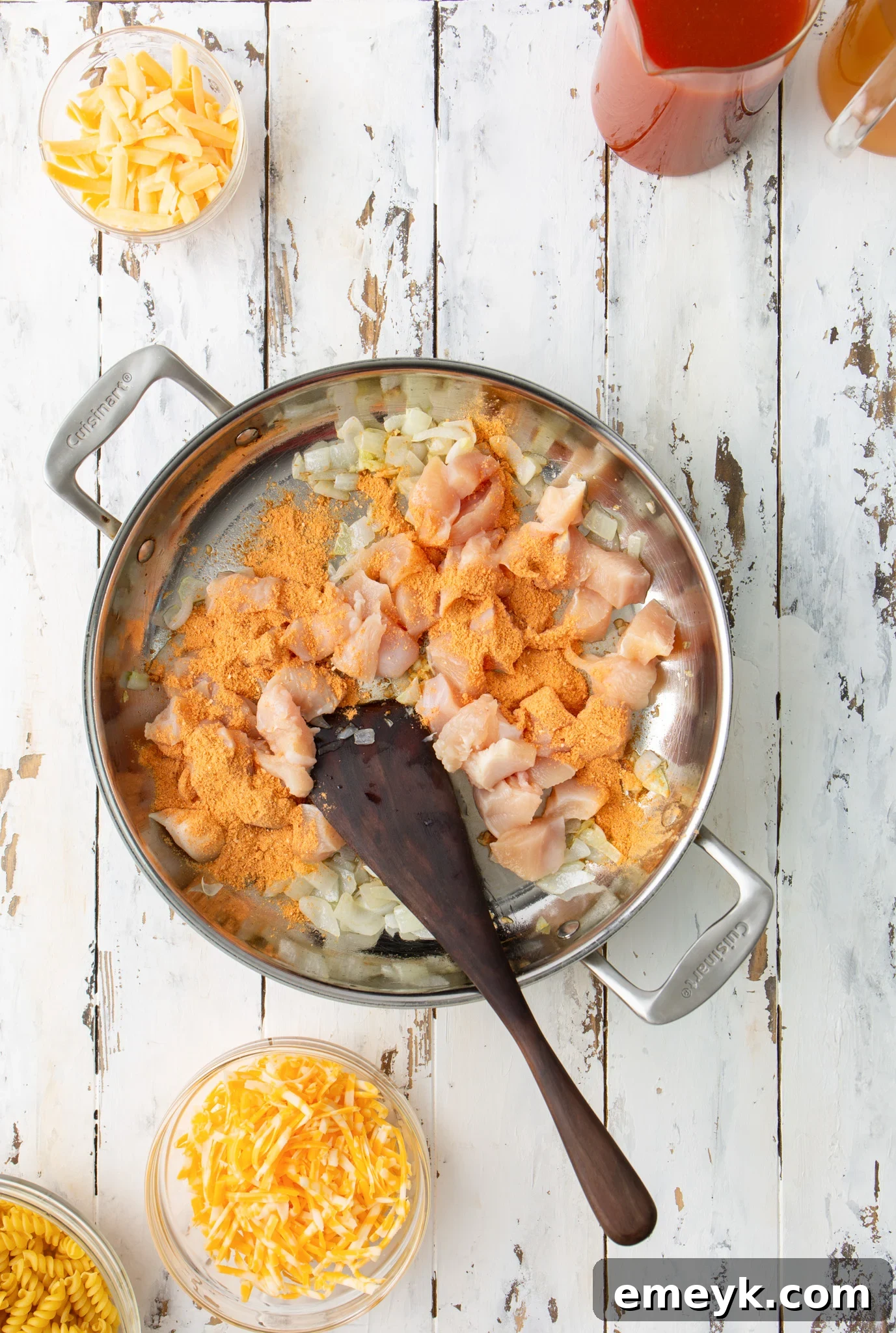 Cubed chicken breast cooking in a skillet with taco seasoning, for One Pot Chicken Enchilada Pasta.