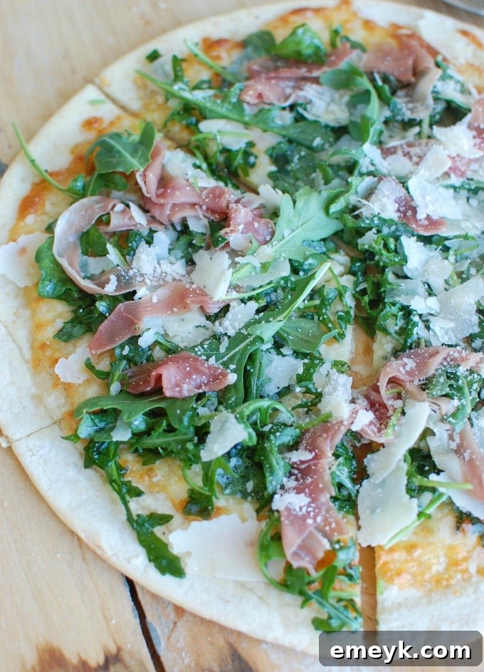 A full Prosciutto Arugula Pizza, freshly topped with vibrant green arugula.