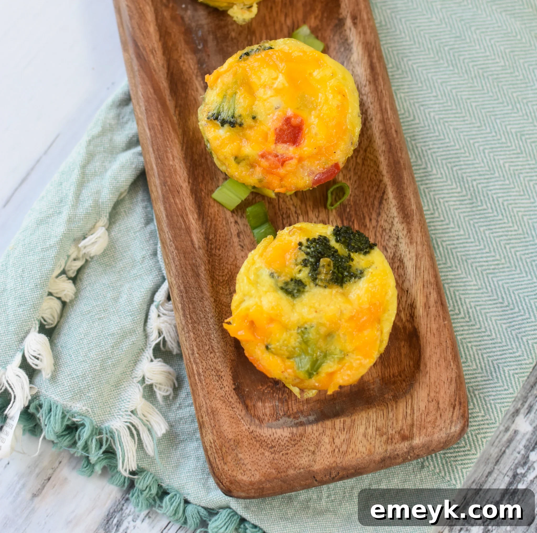 Savory Broccoli Cheddar Bites 2 Broccoli Cheddar Cups on a cutting board, garnished.