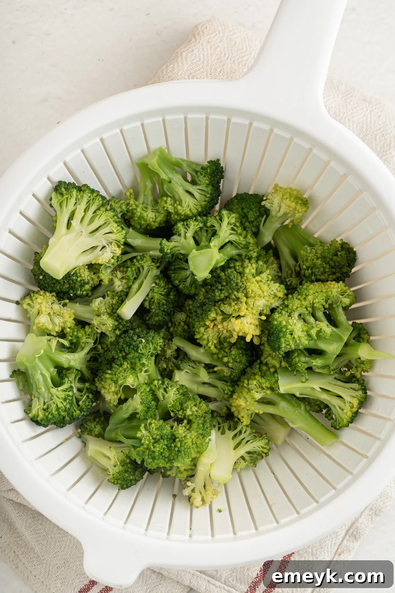 Fresh broccoli florets in a colander, ready for preparation.