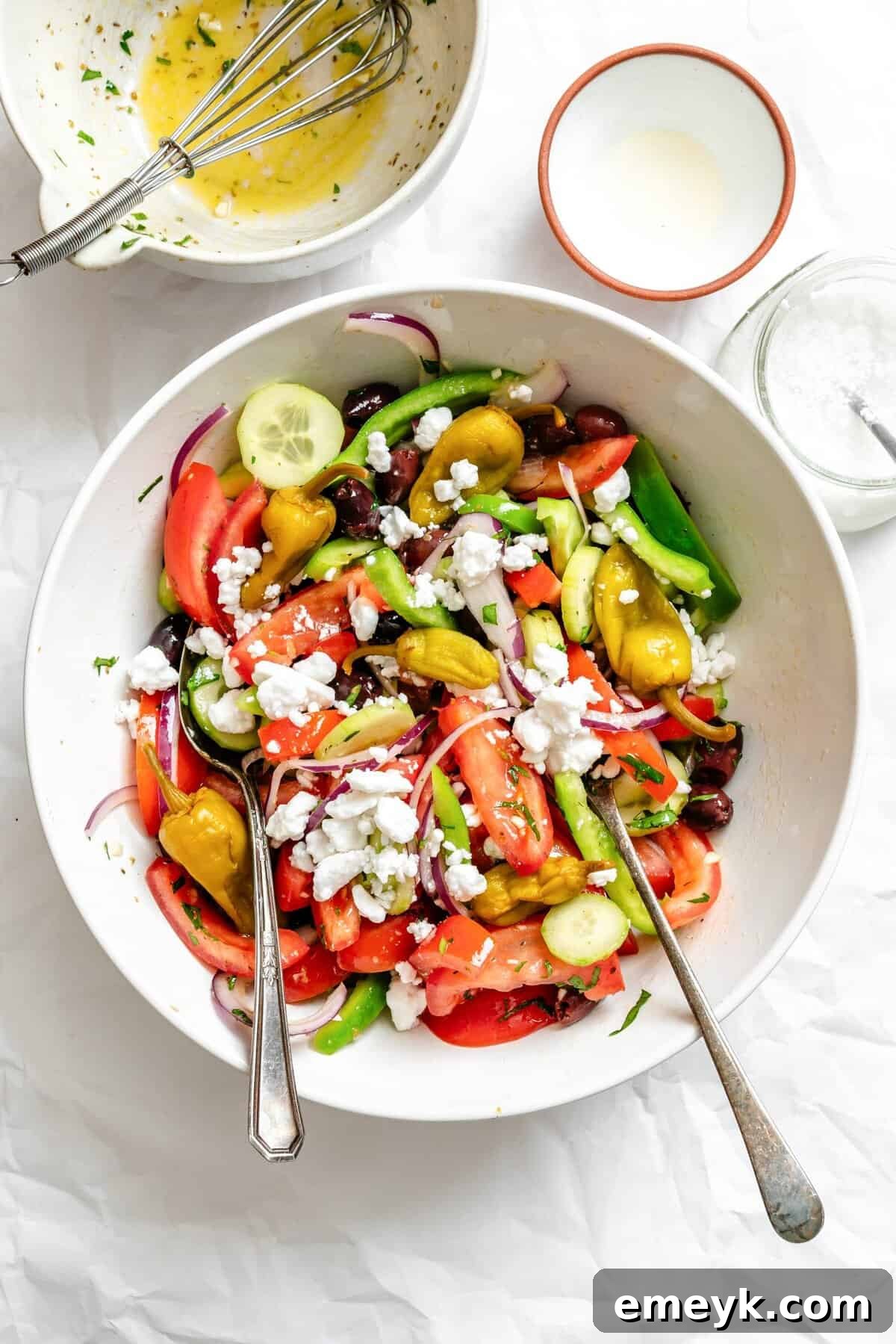 A large bowl of Greek Village Salad with serving spoons, ready to be shared family-style.