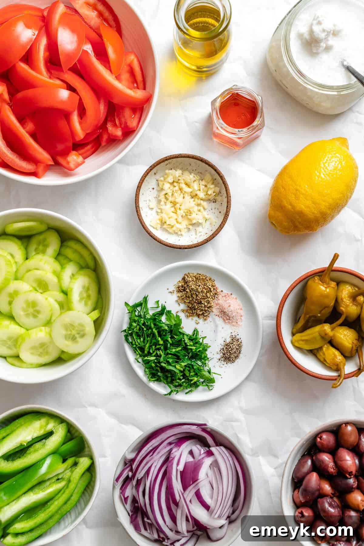 All the fresh and vibrant ingredients laid out for a Greek Village Salad recipe, including vegetables, feta, and olives.