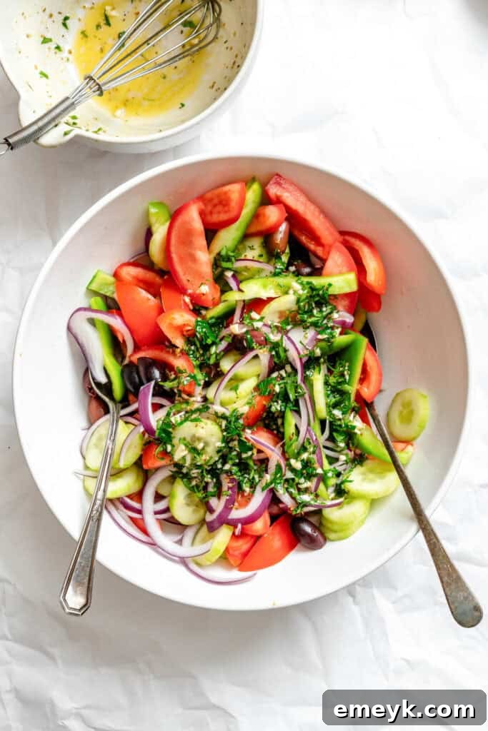 Greek Village Salad vegetables in a bowl with a sprinkle of herbs, waiting for the dressing.
