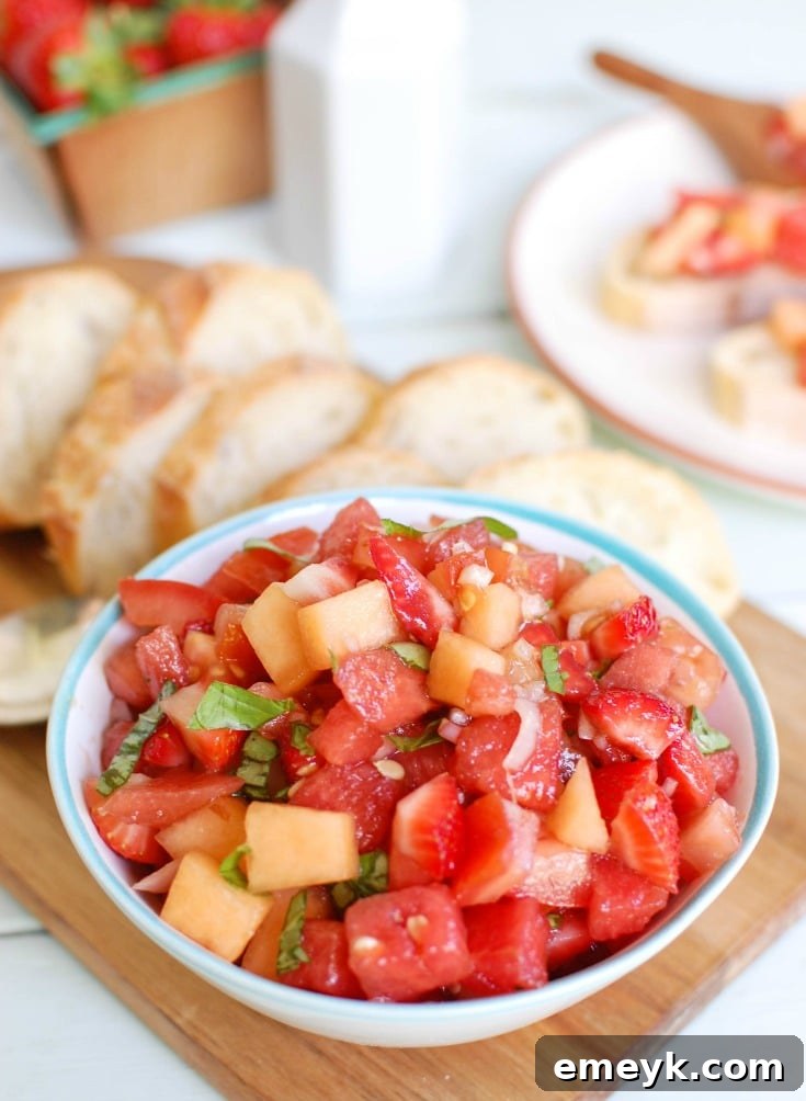 A colorful plate of Berry Melon Bruschetta on toasted baguette slices, featuring diced watermelon, strawberries, and cantaloupe.