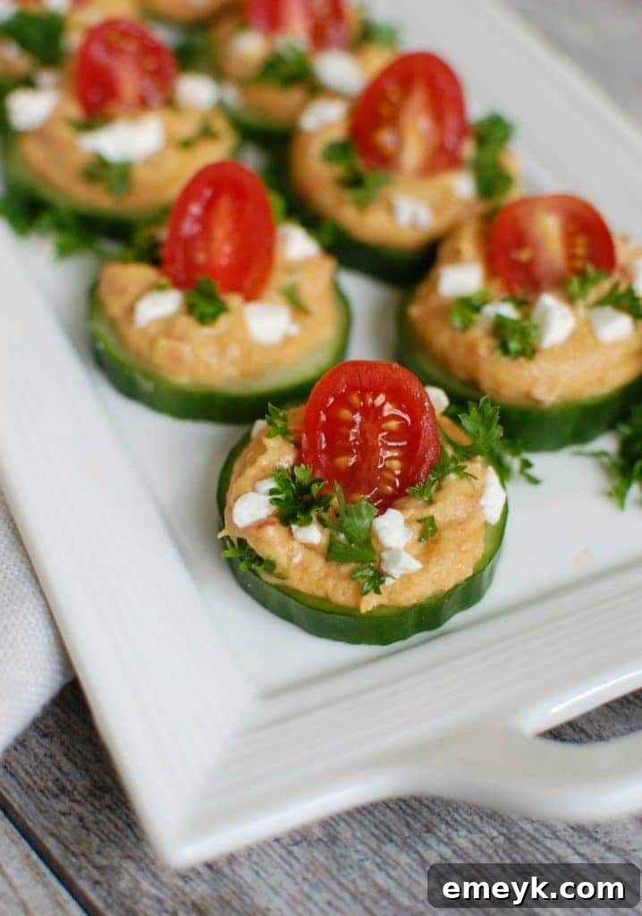 Crisp Cucumber Hummus Medallions 4 A close-up shot of Cucumber Hummus Bites on a white platter, showcasing the fresh toppings and vibrant colors.