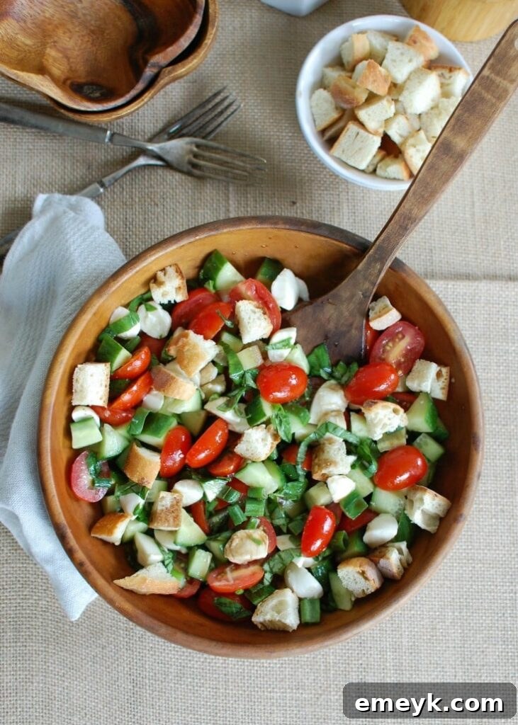 Close-up shot of freshly tossed Caprese Panzanella salad, showcasing juicy tomatoes, mozzarella, basil, and bread.