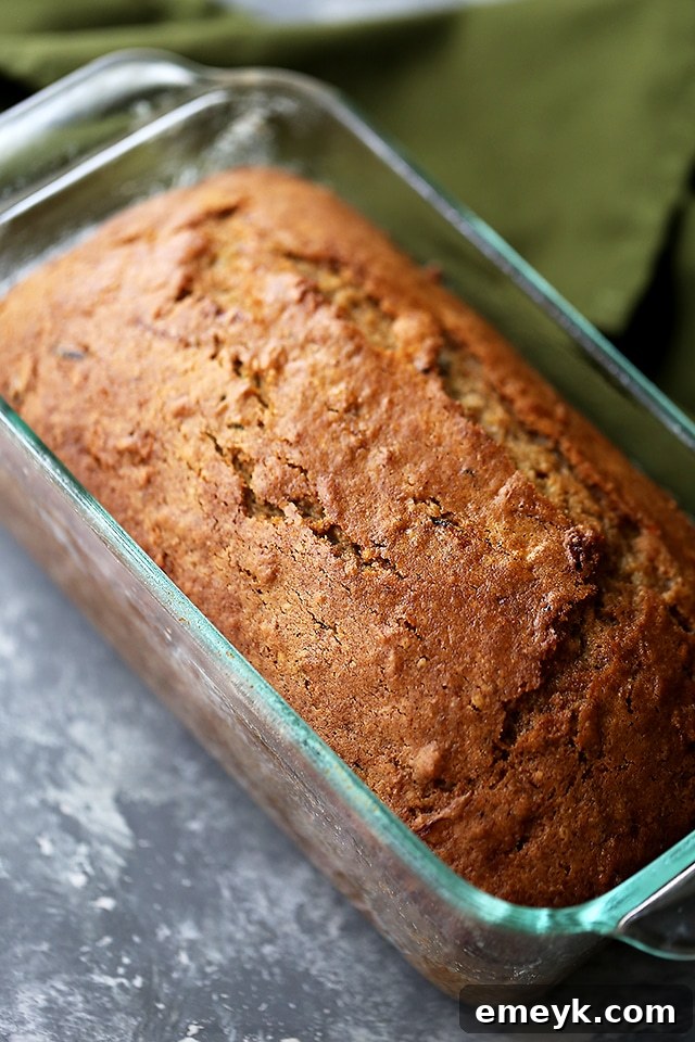 Hearty healthy apple and zucchini bread, sliced to show the moist crumb and studded with apple and zucchini pieces.