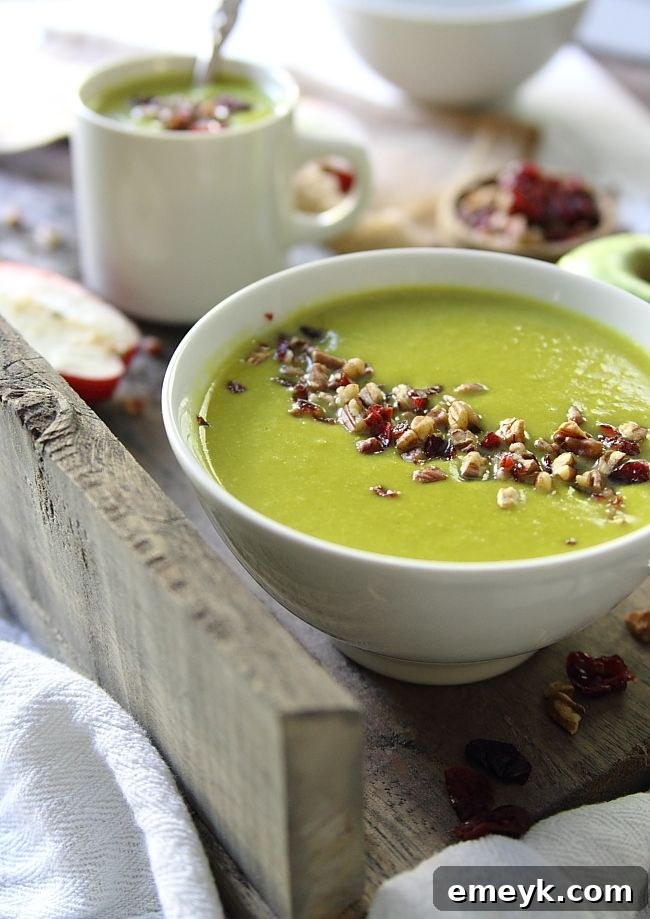 A hearty bowl of Leek Apple Cheddar Soup, garnished with fresh herbs and a swirl of cream.