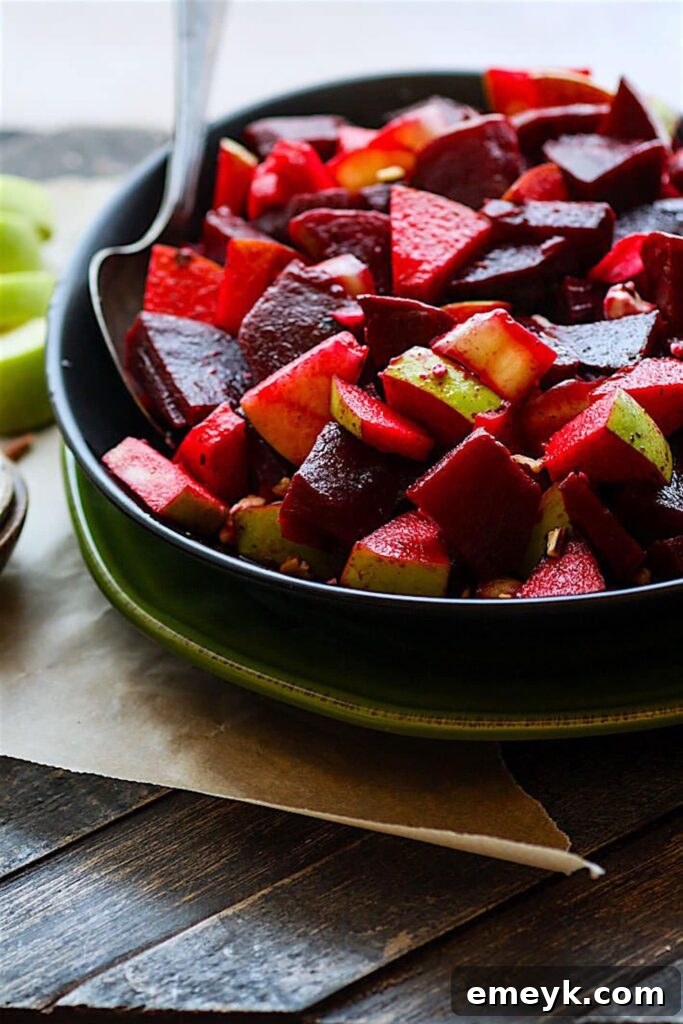 A colorful marinated beet and apple salad, showing thinly sliced beets and apples tossed with dressing.