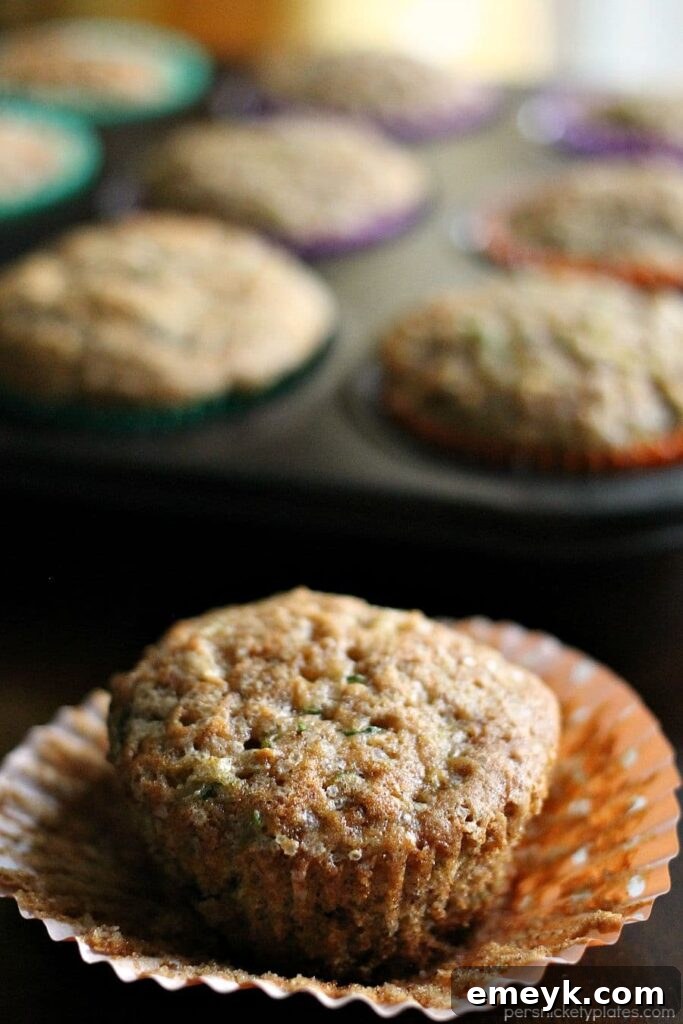 Fluffy apple cinnamon zucchini muffins with a golden-brown top, studded with apple pieces and cinnamon streusel.