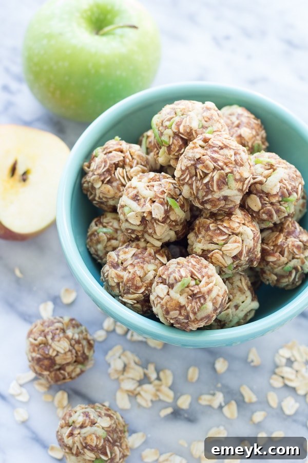 Small, round apple cinnamon cookie energy bites on a plate, sprinkled with cinnamon and oats.