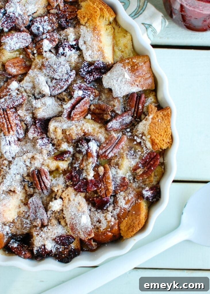 Overnight Eggnog French Toast Bake with Cranberry Maple Syrup, served in a white baking dish.