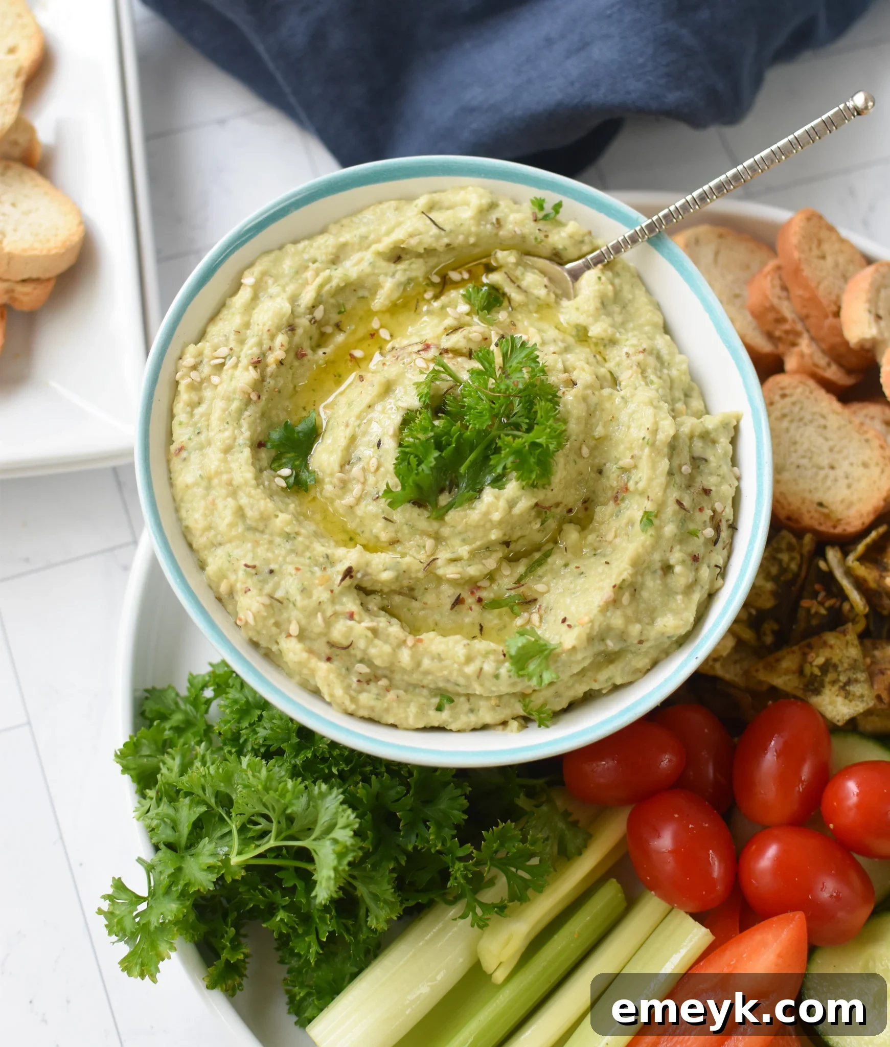 White Bean Artichoke Dip served with a variety of crostini and fresh cut vegetables, showcasing its versatility as an appetizer.