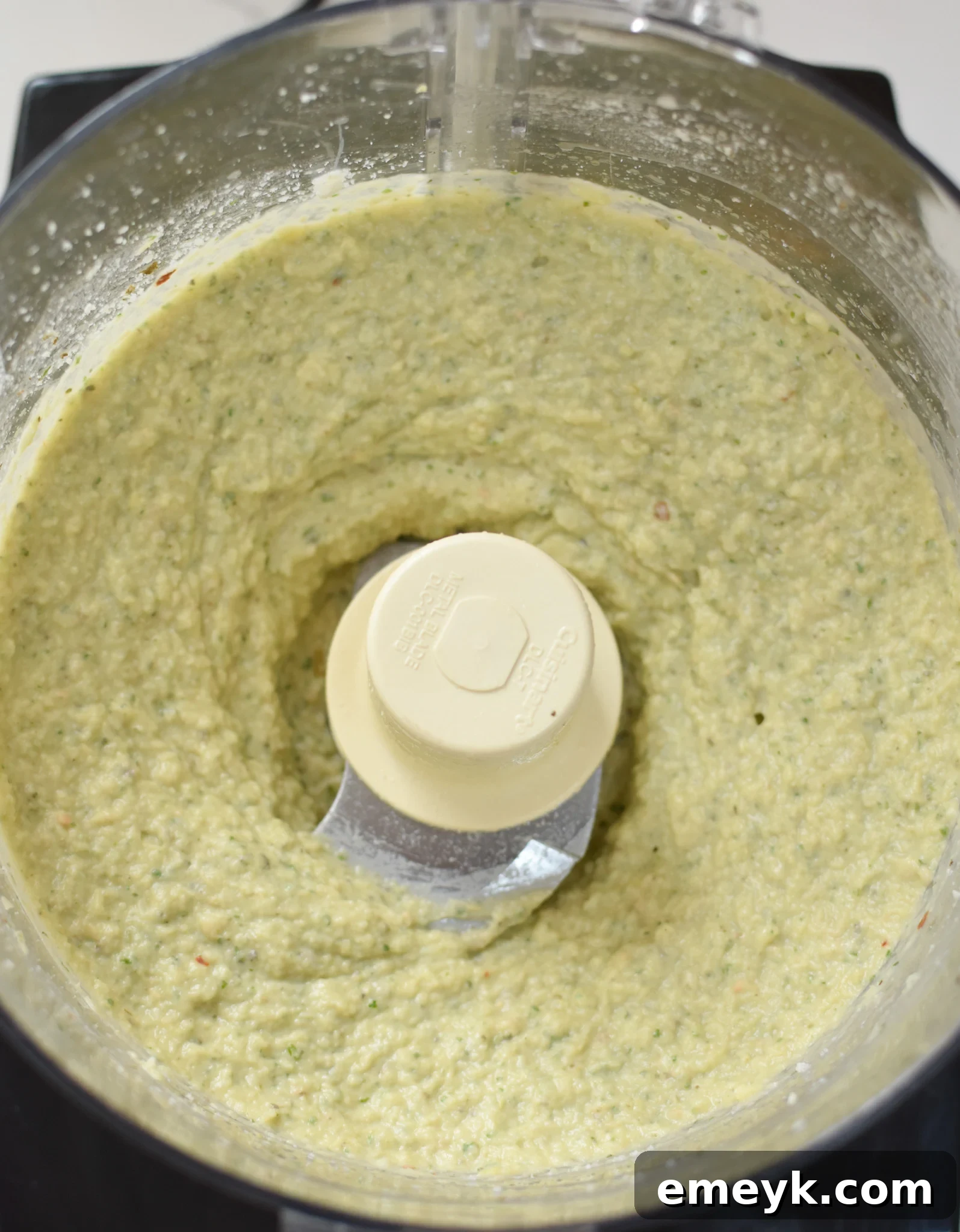 A close-up shot of the creamy White Bean Artichoke Dip in a serving bowl, showcasing its smooth texture and fresh garnish.