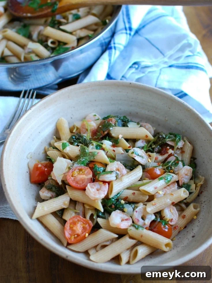 Vibrant Shrimp, Kale & Artichoke Pasta 2 A vibrant bowl of Shrimp Kale Artichoke Pasta, featuring pink shrimp, green kale, artichoke hearts, red cherry tomatoes, and pasta, all tossed in a light lemon sauce.