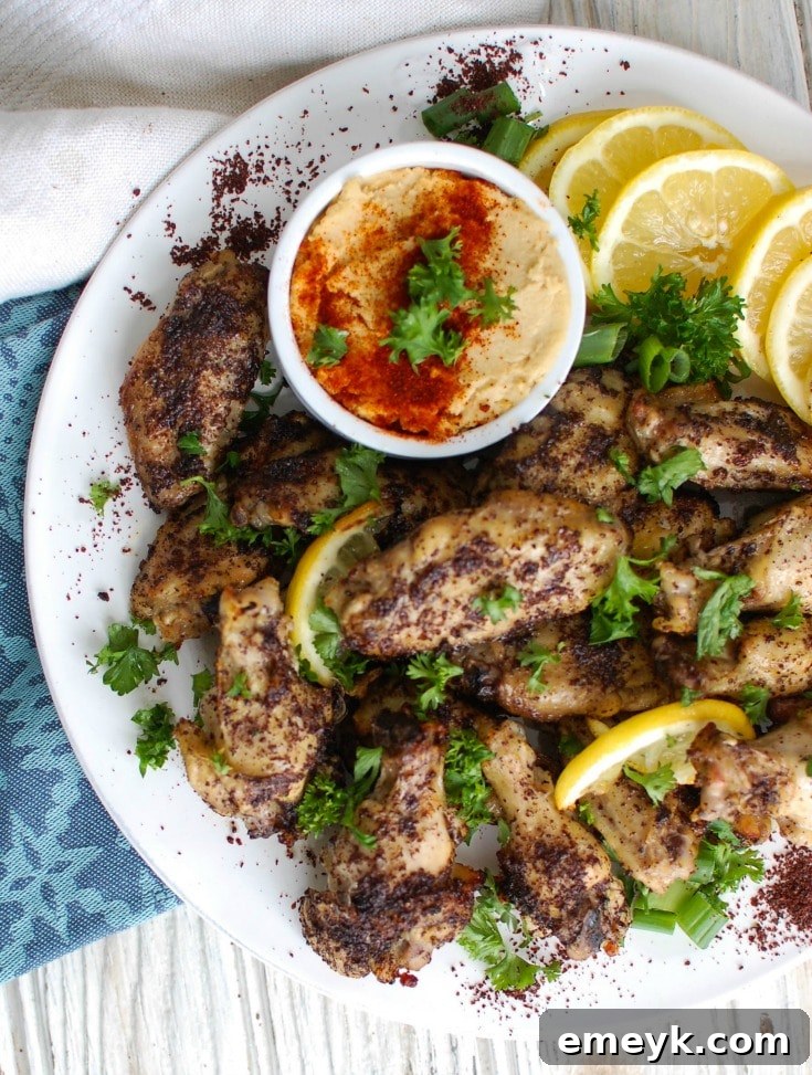 A beautifully presented platter of Sumac Lemon Baked Chicken Wings, garnished with herbs and fresh lemon, ready for a feast.