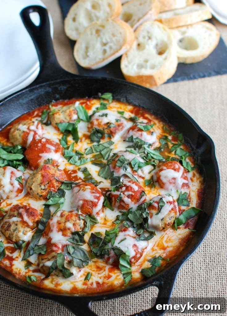 Skillet Tomato Basil Meatballs baking in the oven, with cheese melting and bubbling.