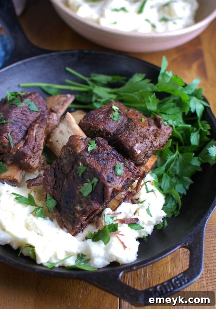 Plated Slow Cooker Red Wine Short Ribs, tender and juicy, served with creamy mashed potatoes and fresh herbs, ready for a romantic dinner.