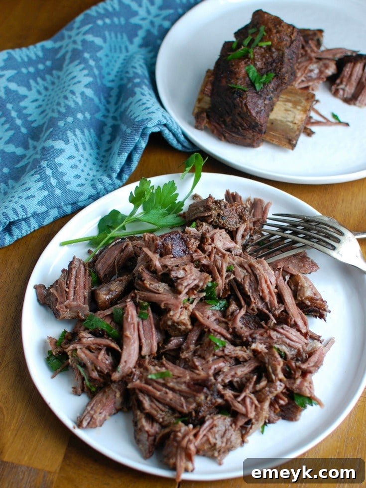 Cooked Slow Cooker Red Wine Short Ribs, resting on a bed of creamy mashed potatoes with fresh herbs and rich sauce.