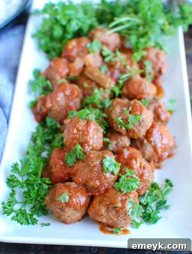 A close-up shot of Slow Cooker Mediterranean Beef Meatballs with Lebanese Green Beans, garnished with fresh parsley, served over rice.