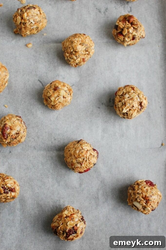 Formed Cranberry Almond Energy Bites placed on a baking sheet lined with wax paper, ready for refrigeration.
