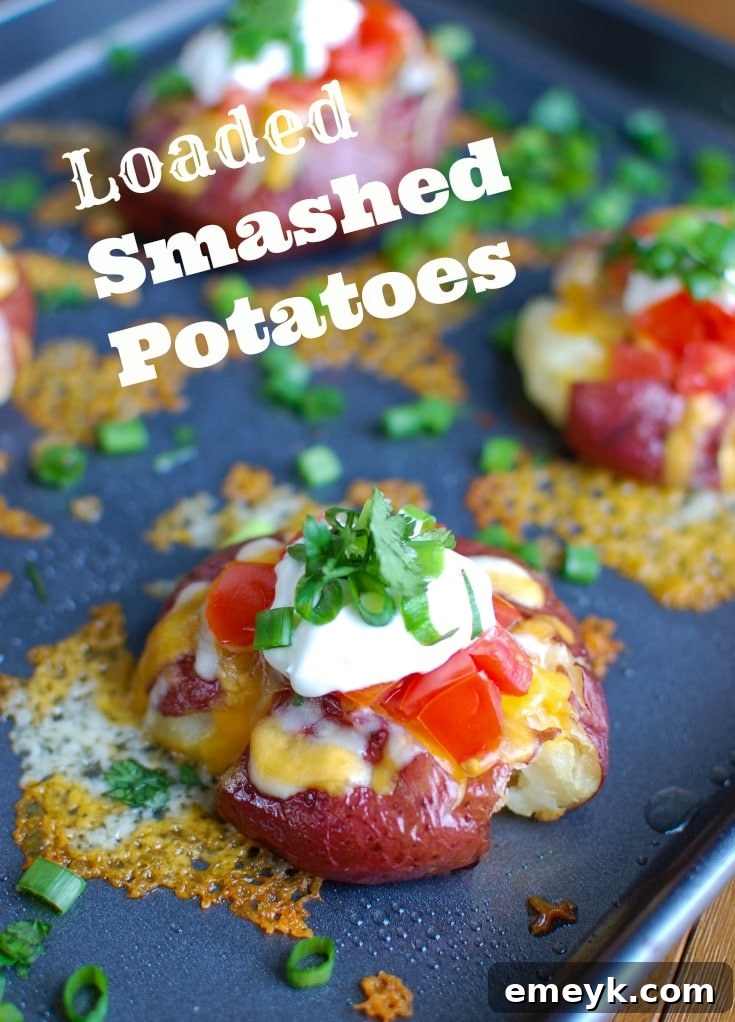 Crispy Loaded Smashed Potatoes with melted Sargento cheese, sour cream, tomatoes, green onions, and cilantro, served on a white plate with a side of extra toppings.