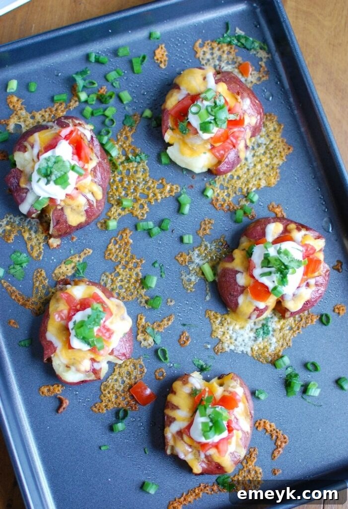A serving of Loaded Smashed Potatoes garnished with sour cream, green onions, and cilantro, presented on a rustic wooden board.